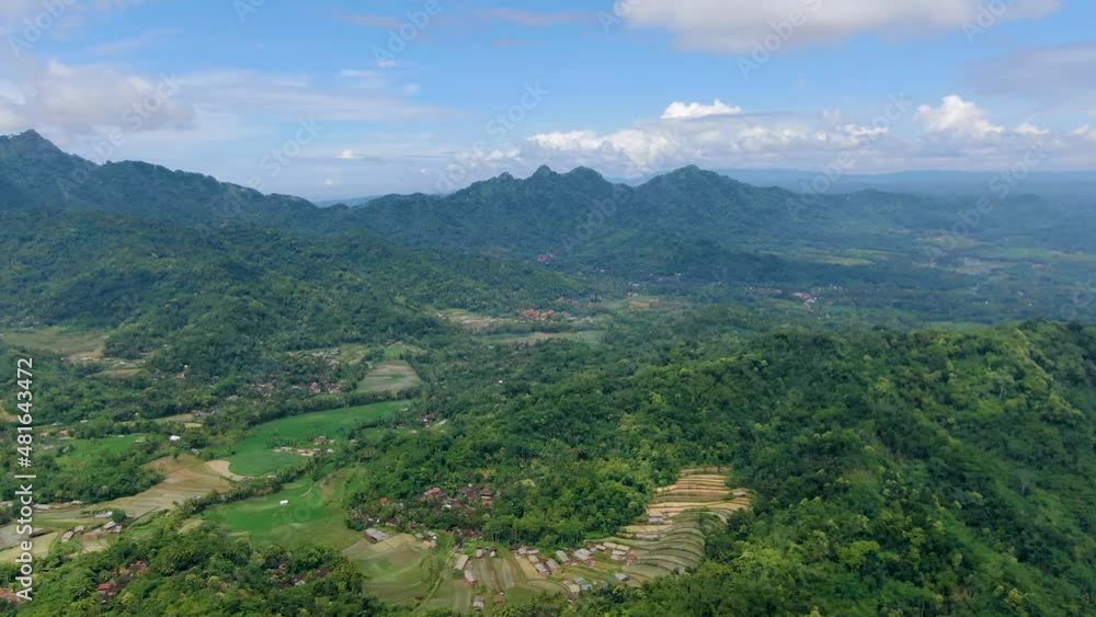 Drone flying over verdant valley with Menoreh hills in background, Muntilan in Indonesia. Aerial forward Drone flying over verdant valley with Menoreh hills in background, Muntilan in Indonesia. Aerial forward