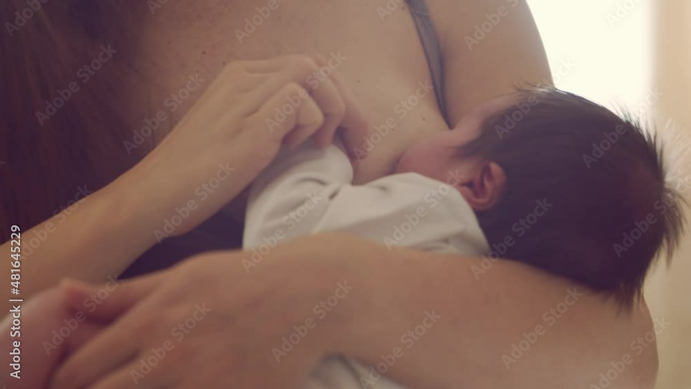 Mom breastfeeds a nursing baby. Close-up portrait of the infant and his mother. Window light. Mom breastfeeds a nursing baby. Close-up portrait of the infant and his mother. Window light.
