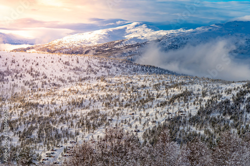 Beautiful Snow Landscape aerial view, background during sunrise with fog mountain range in the background, forest with trees in the forefront, ski area, stryn, norway