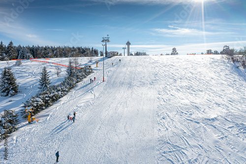 Flight over the ski resort in Willingen Upland. Hochheideturm appears behind the slope. Camera flies in the air. Slope almost deserted.