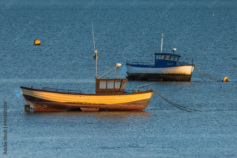 Moored boat illuminated by the rays of the setting sun on the shoal during low tide Moored boat illuminated by the rays of the setting sun on the shoal during low tide