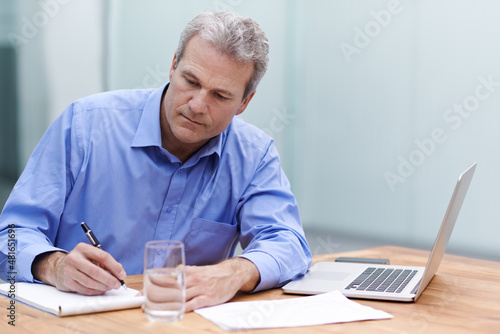 One idea deserves another. Shot of a mature businessman writing notes at his desk in the office.