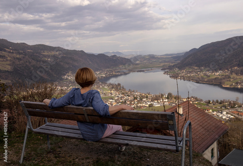 A woman sits on a bench on the shore of the lake