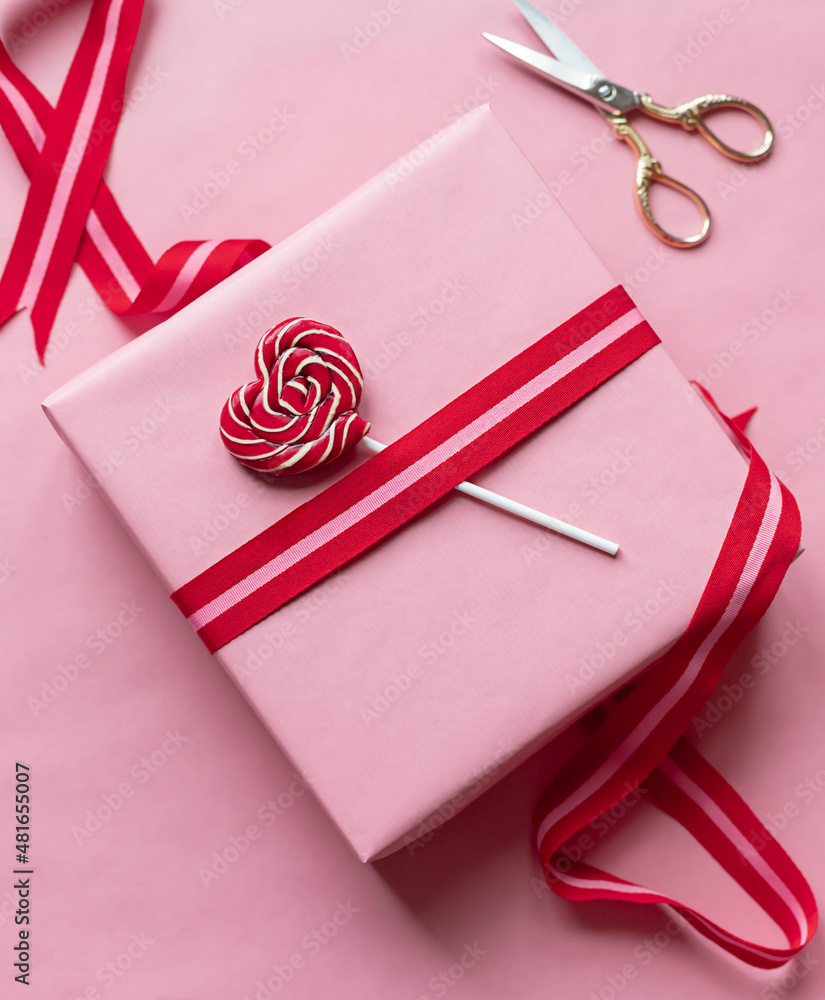 Fototapeta premium Valentine's day celebration gift box and heart shaped lollipop on the pink background. Close up 