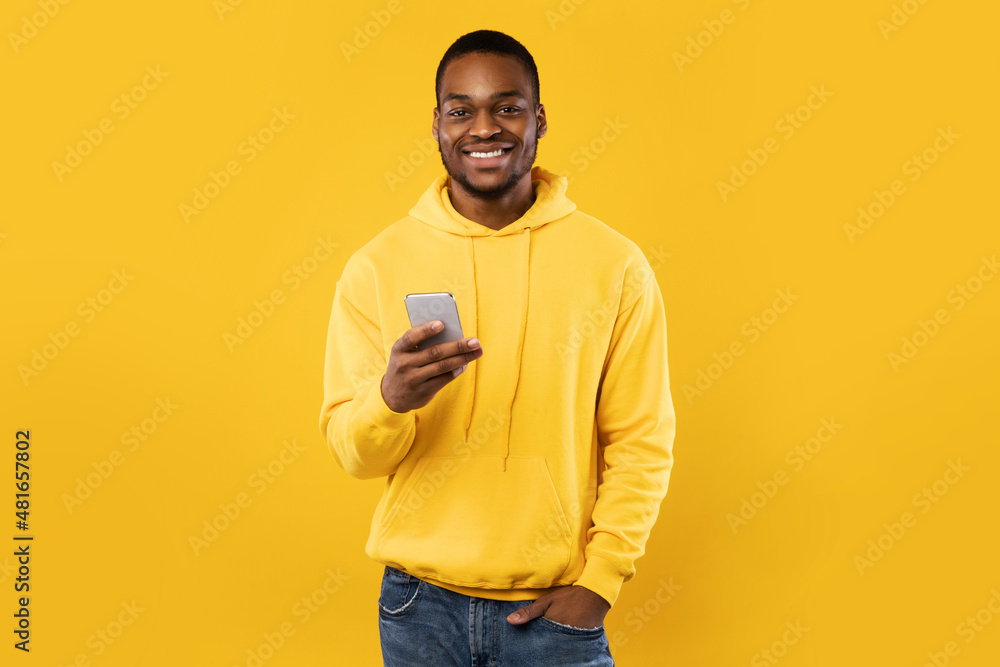 Happy Black Millennial Man Using Mobile Phone Over Yellow Background Happy Black Millennial Man Using Mobile Phone Over Yellow Background