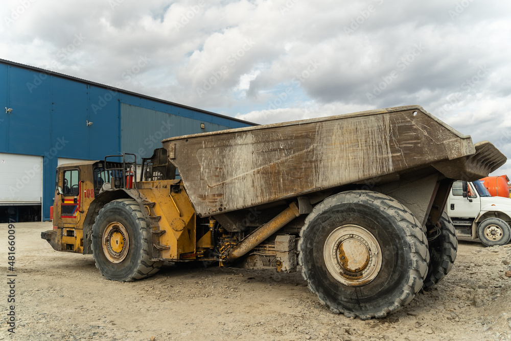 An underground truck stands at a gold mining site near a structure.