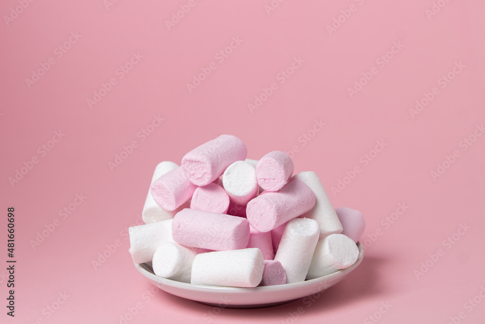Marshmallows on a pink background. Colored marshmallows on a white plate. Delicate dessert