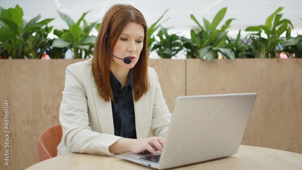 Emergency line operator wearing headset talking to caller and typing on laptop, tracking shot. Help desk consultant giving online support. Concept of technology Emergency line operator wearing headset talking to caller and typing on laptop, tracking shot. Help desk consultant giving online support. Concept of technology