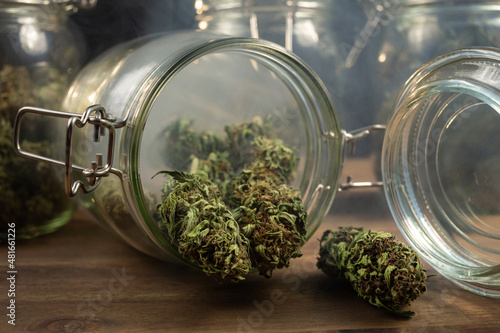 Dry CBD hemp buds, cannabis potheads spilled from a glass jar on the table.