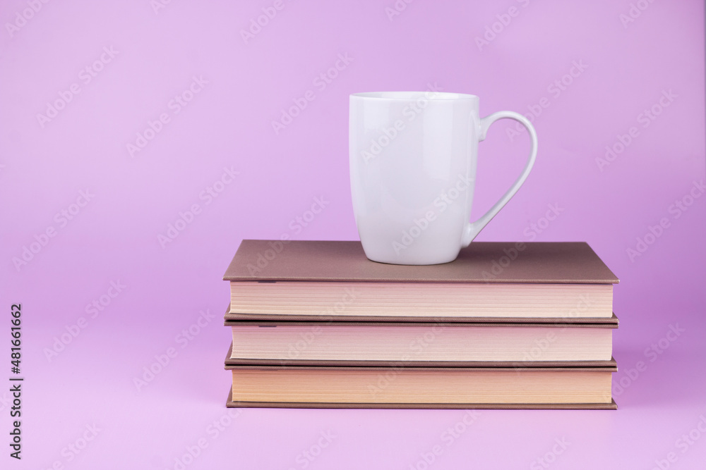 White cup with coffee or tea is on stack of books on pink background. Education mock up concept with copy space. White cup with coffee or tea is on stack of books on pink background. Education mock up concept with copy space.