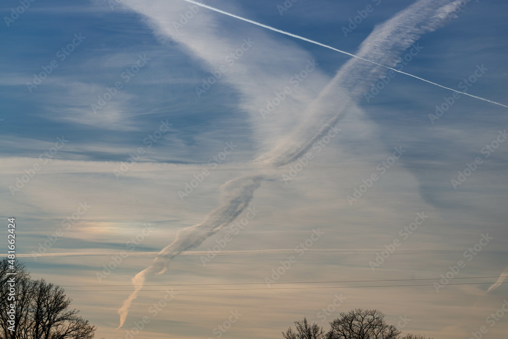 Chmury kondensacyjne po przelocie samolotu na błękitnym niebie. - obrazy, fototapety, plakaty 