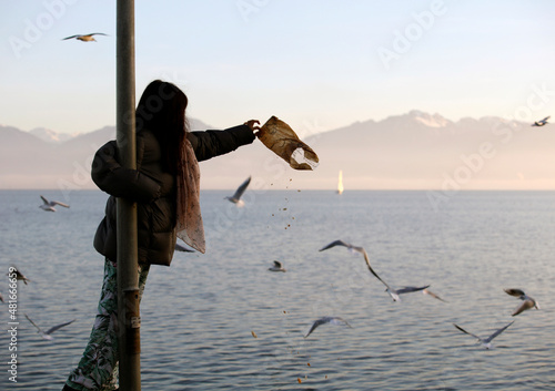 Fotografie Une fillette en contre-jour donne des miettes aux mouettes