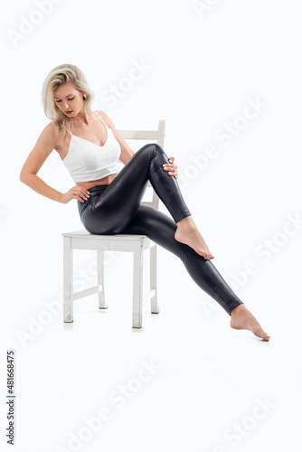 Beautiful blonde girl sitting on a chair in a bright studio