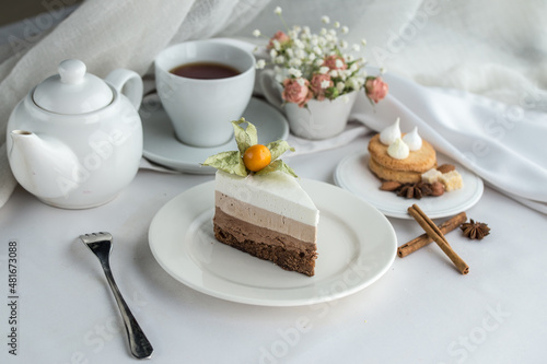 Slice of Triple Chocolate mousse Cake and cup of tea on the table