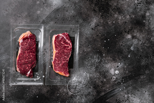 New-York steak pack, on black dark stone table background, top view flat lay, with copy space for text