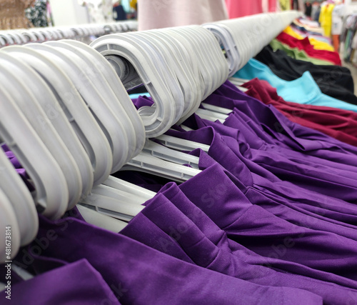 Fashion clothes on clothing rack - bright colorful closet. Closeup of rainbow color choice of trendy female wear on hangers in store closet or spring cleaning concept. Summer home wardrobe...