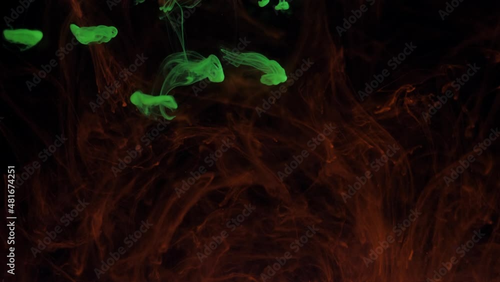 Mixing particles of glowing colors of green and red paint in smoke. Mixing particles of glowing colors of green and red paint in smoke.