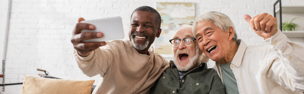 Positive multicultural men using mobile phone at home, banner. Positive multicultural men using mobile phone at home, banner.