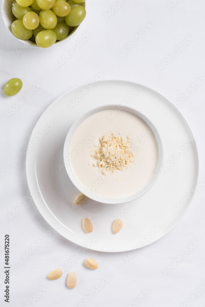 Crema de almendras, sopa fría española. Ajo blanco de Málaga con almendras y uvas en un recipiente blanco sobre una mesa blanca Crema de almendras, sopa fría española. Ajo blanco de Málaga con almendras y uvas en un recipiente blanco sobre una mesa blanca