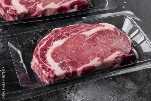 Marbled beef from the store, on black dark stone table background, with copy space for text