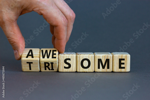 Awesome or trisome symbol. Doctor turns wooden cubes and changes the concept word awesome to trisome. Beautiful grey table, grey background, copy space. Medical, awesome or trisome concept.