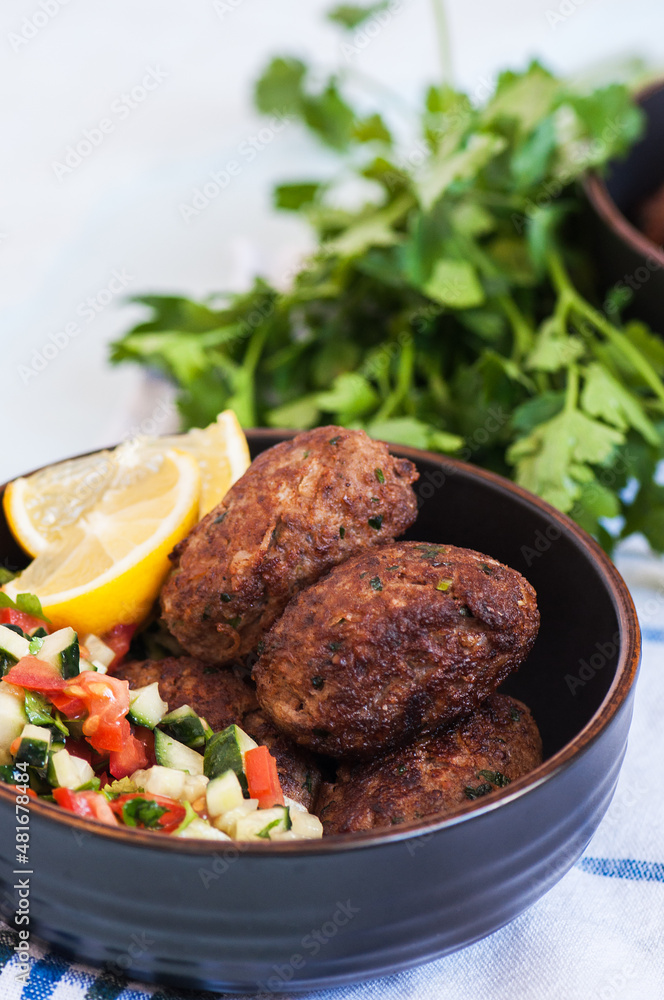 Fried minced meat kofta or kebabs served with vegetable saladf in a bowl. Close up. Middle eastern food concept.