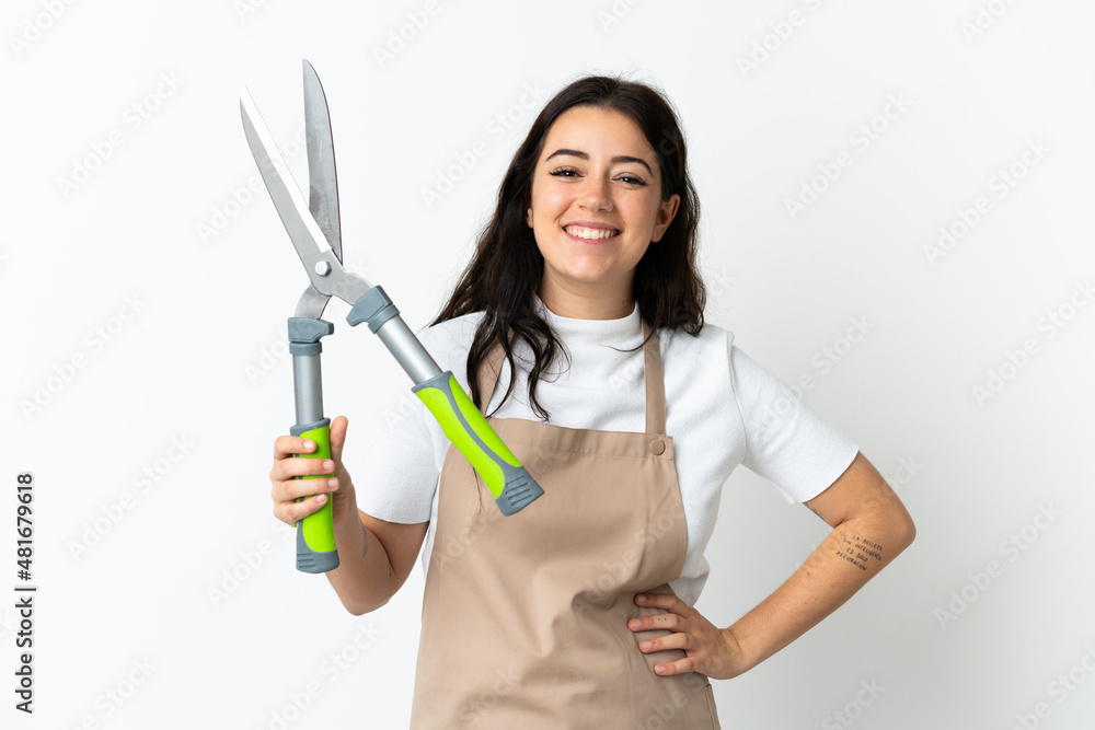 Young caucasian woman holding a plant isolated on white background posing with arms at hip and smiling Young caucasian woman holding a plant isolated on white background posing with arms at hip and smiling