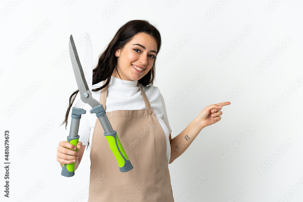 Young caucasian woman holding a plant isolated on white background pointing finger to the side Young caucasian woman holding a plant isolated on white background pointing finger to the side