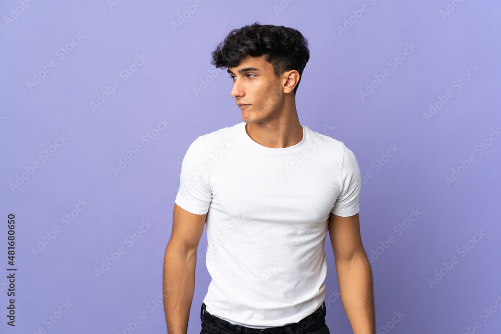 Young Argentinian man isolated on background making doubts gesture looking side Young Argentinian man isolated on background making doubts gesture looking side