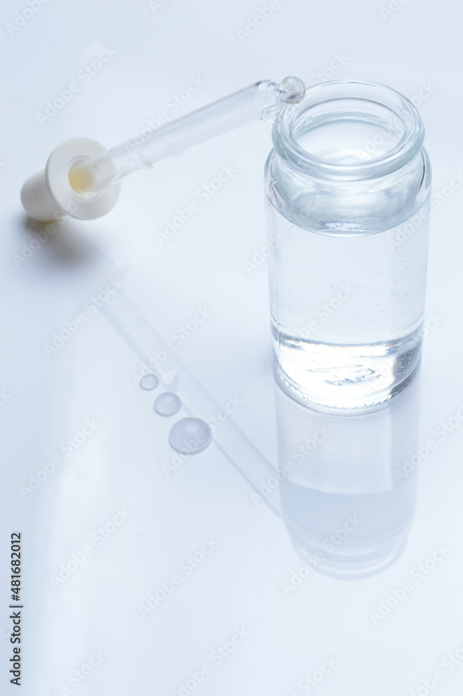 glass transparent jar and a cosmetic pipette with liquid droplets on a white background. glass transparent jar and a cosmetic pipette with liquid droplets on a white background.