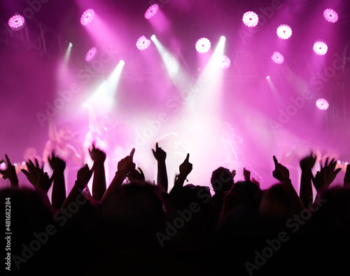 Throw your hands up. Rearview of an audience with hands raised at a music festival and lights streaming down from above the stage.