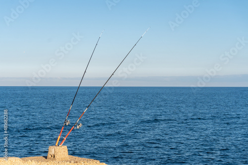 Two isolated fishing rods with the sea in the background