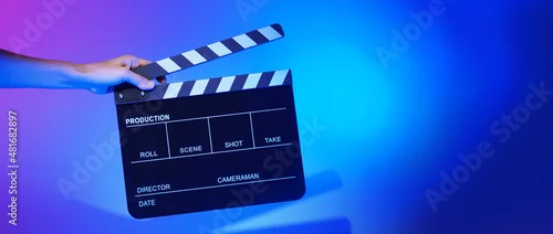 Panel kuchenny z motywem Blurry images of movie slate or clapper board. Hand holds empty film making clapperboard on color background in studio for film movie shooting or recording. Film slate for Youtuber video production.