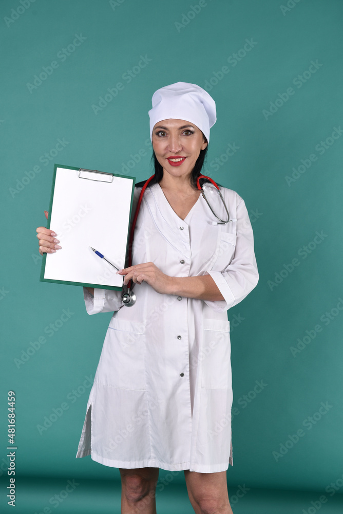 A female doctor in a white coat and a white headdress shows recordings on a tablet with a stethoscope on a green background A female doctor in a white coat and a white headdress shows recordings on a tablet with a stethoscope on a green background