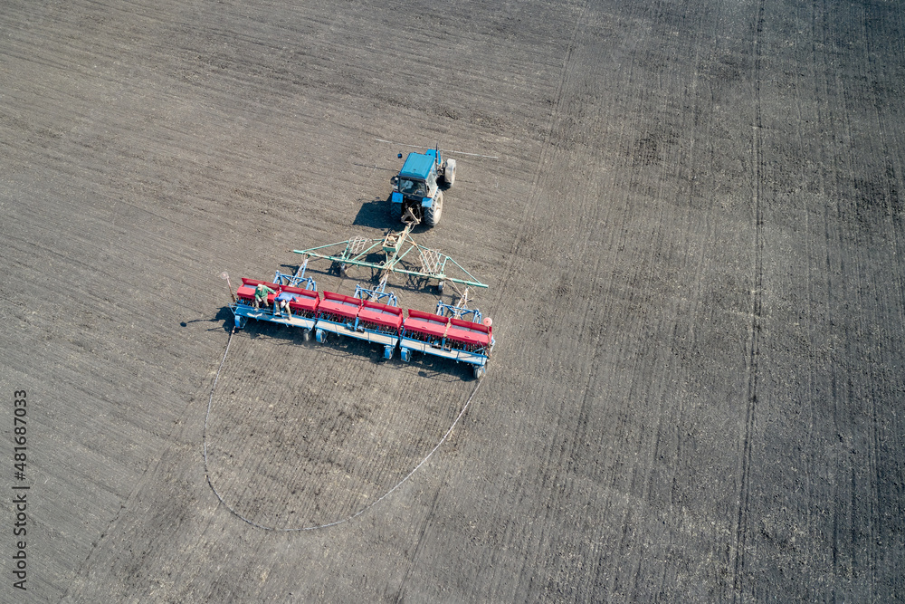 Fototapeta Seeding. Tractor work with a seeder in the field. Shooting from a drone. Copy space.