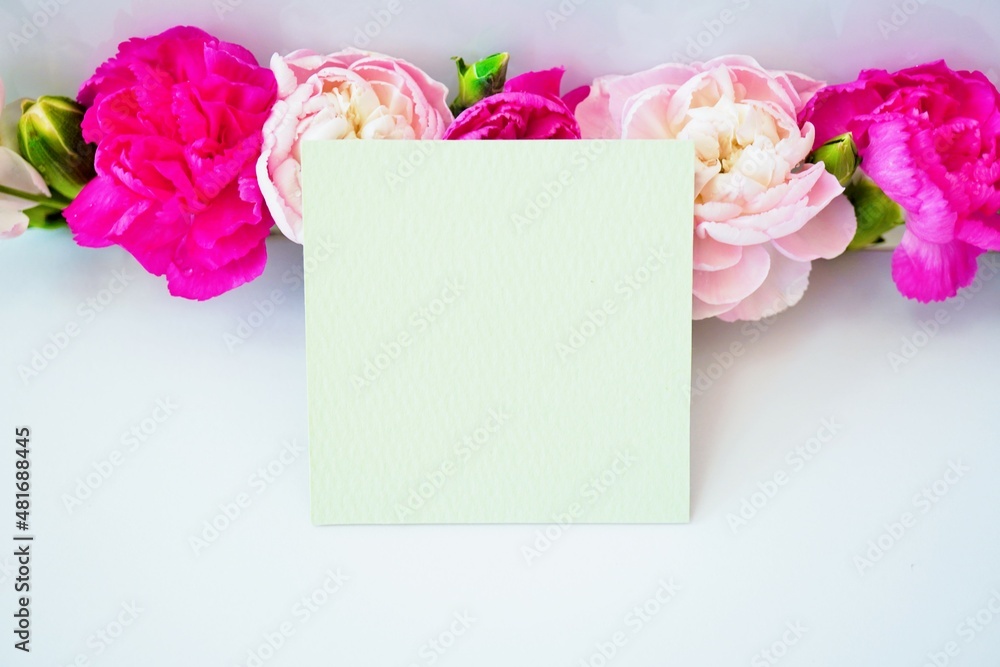 一列に並んだ赤とピンク色のカーネーションの花を背景にしたマザースデーのカードのモックアップ