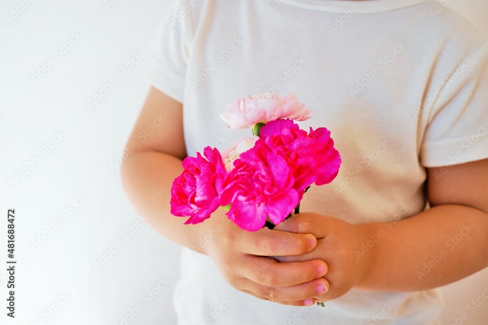 赤ちゃんが握る赤とピンクのカーネーションの花のブーケ