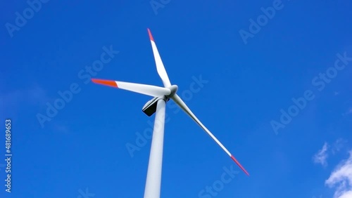 Single wind turbine spins under a blue sky and generates clean and environmentally friendly electricity.