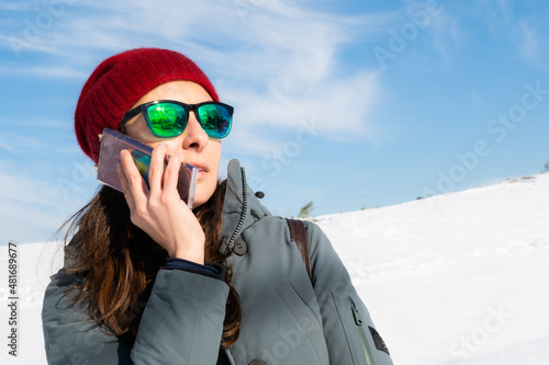 Beautiful glamorous woman talking on her cell phone in a beautiful snowy landscape