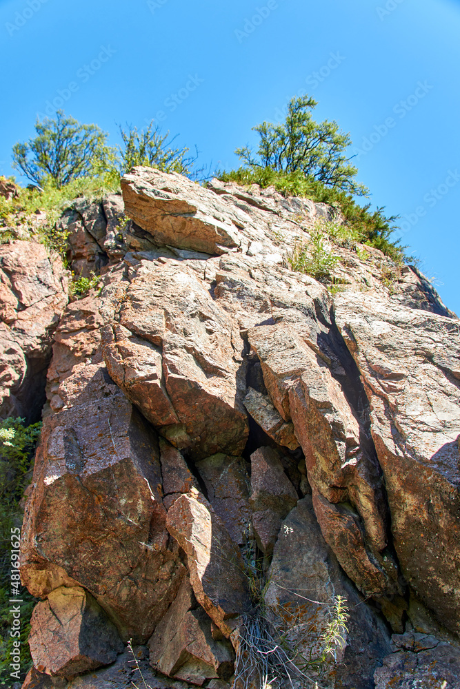 rocky cliff with cracks with trees on the top