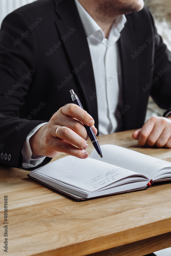 man's hand with a pen over a diary
man writes in his diary
