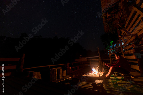 Campfire under night sky with stars and Milky way. Night camping. Hiking tourist have a rest in her campfire