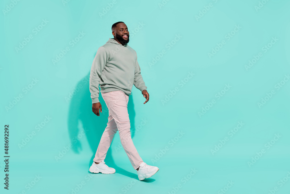 Full length body size view of cheery attractive guy walking copy space isolated over bright teal turquoise color background Full length body size view of cheery attractive guy walking copy space isolated over bright teal turquoise color background