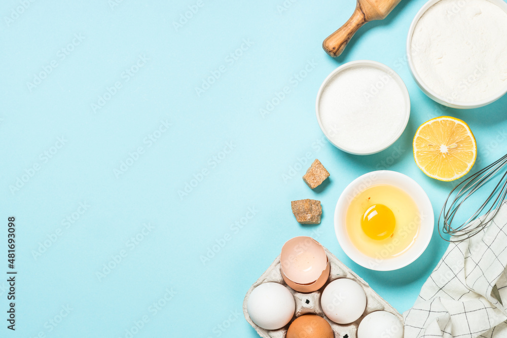 Baking ingredients at blue table. Flour, sugar, eggs and utensils. Top view with copy space. Baking ingredients at blue table. Flour, sugar, eggs and utensils. Top view with copy space.