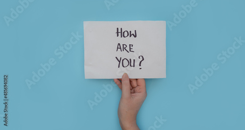 Hand holding How are you note over blue background