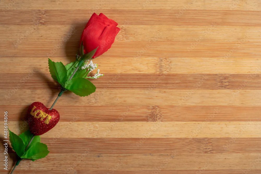 Valentine's Day backgrounds with a Red plastic roses on a wooden table for the concept of love.