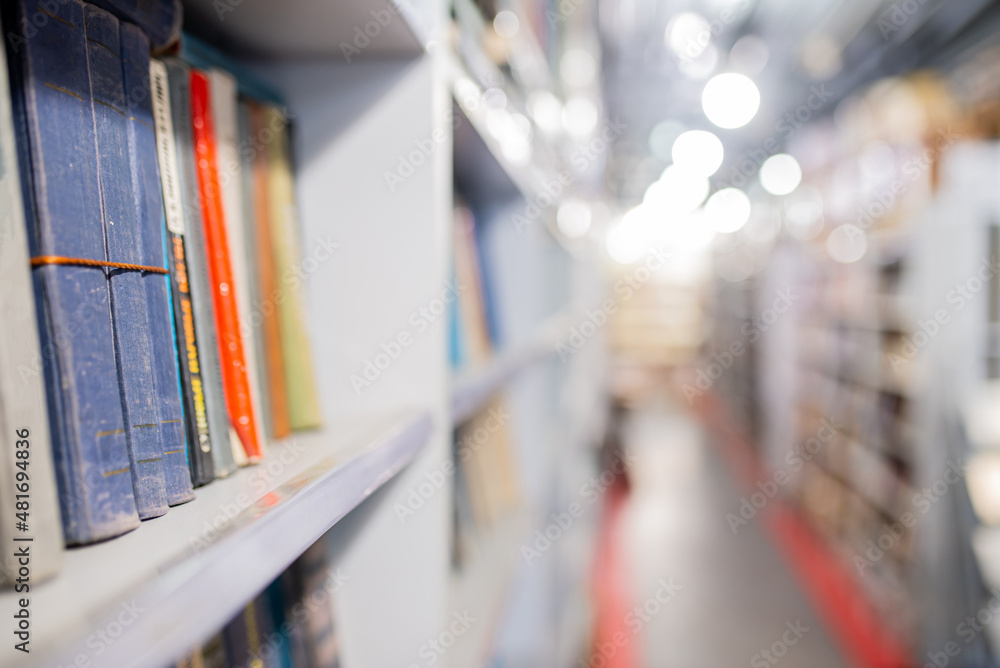 Blurred image of a library with bookcases. Many different books on the shelves. Large selection of books in a bookcase. Blurred background. Blurred image of a library with bookcases. Many different books on the shelves. Large selection of books in a bookcase. Blurred background.