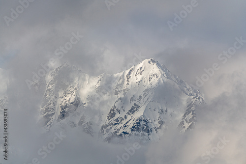 Misty, cloudy snow capped mountain top in northern Canada, Yukon Territory with blue sky background. Great for wallpaper, desktop view. 