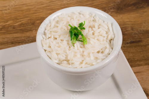 A bowl of white rice cooked in a white bowl on a wooden background