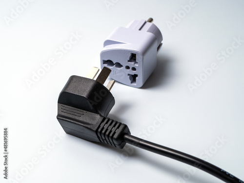 An electrical plug lying next to an adapter for another type of electrical plug. photo